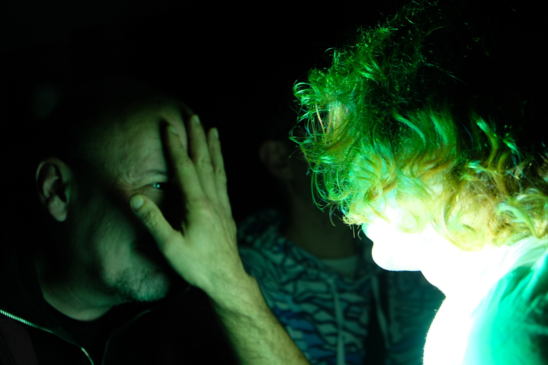 Close performance encounter illuminated by green projection light.
