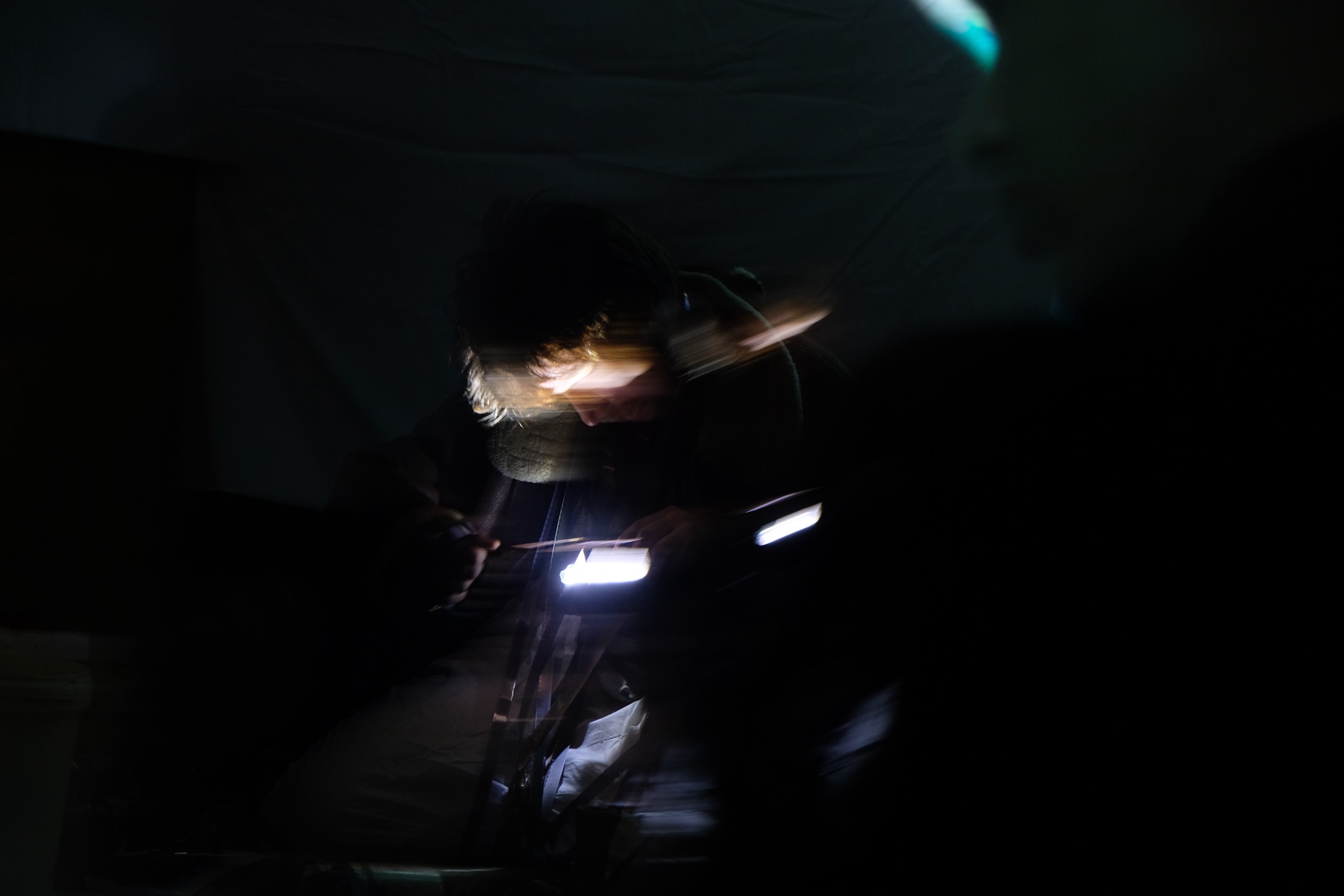 Long-exposure figure holding lights in the dark performance space.