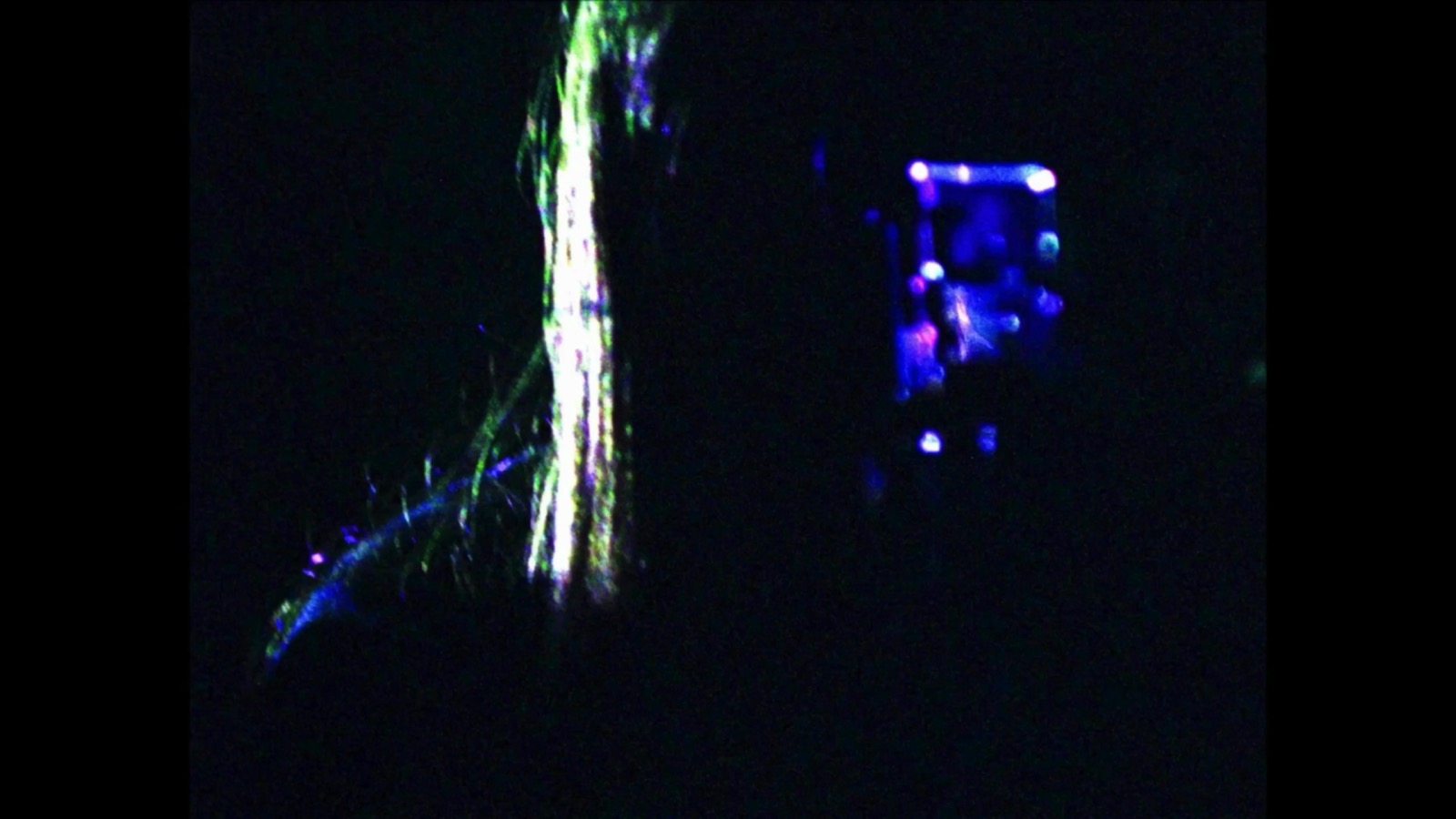 Blue-violet reflected figure emerging from darkness in Skull And Stare Alone.